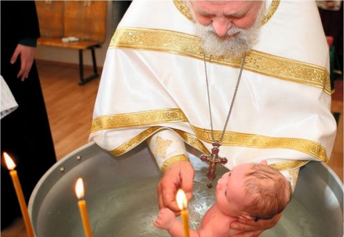 батюшка с мальчиком-младенцем совершает обряд Крещения после выбора имени ему