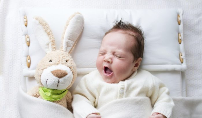новорожденный мальчик после Крещения и выбора имени лежит в кроватке с зайцем