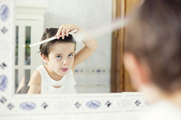Мальчик у зеркала укладывает причёску