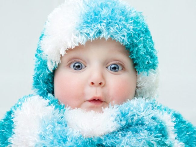 Новорождённый ребёнок в шапочке и шубке из голубой травки