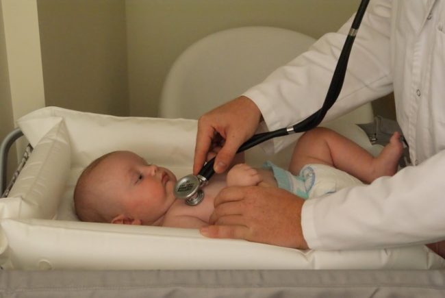 Новорождённый прослушиваемый стетоскопом