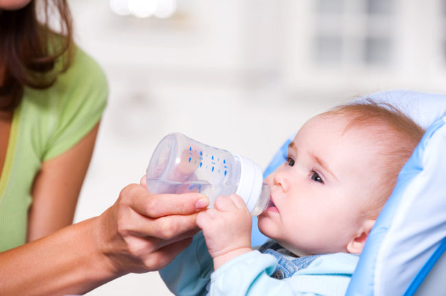 Мама поит новорождённого ребёнка водой из бутылочки