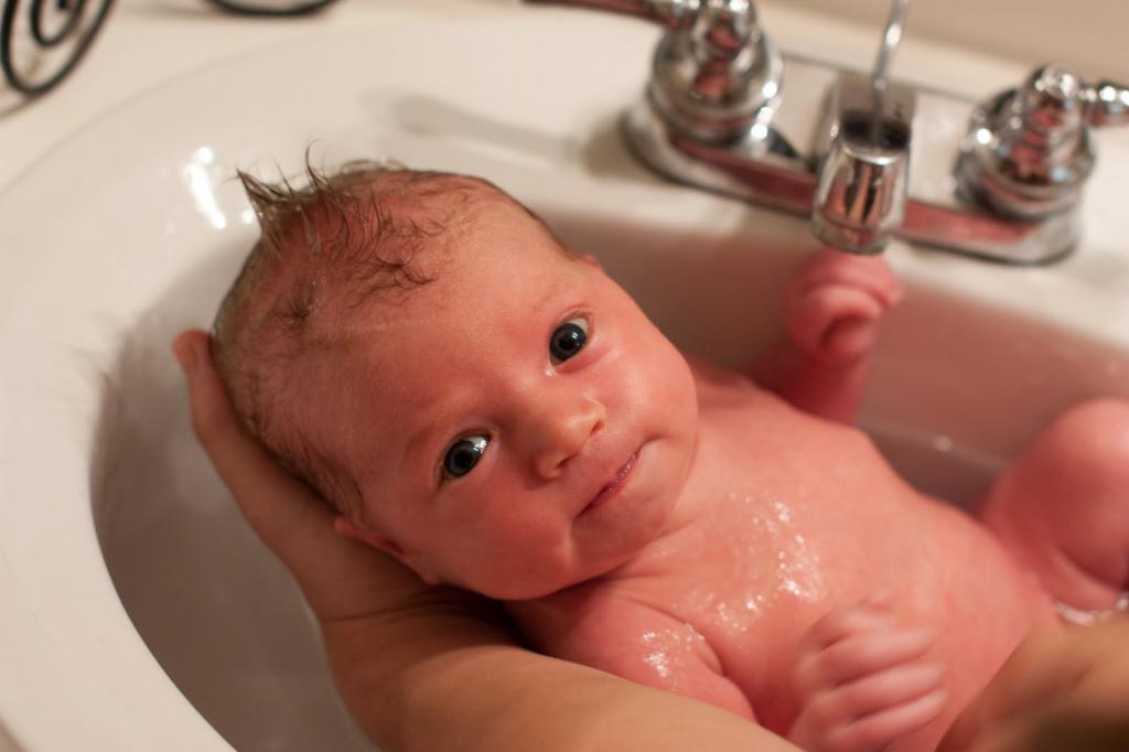 Как держать новорожденного при подмывании под краном