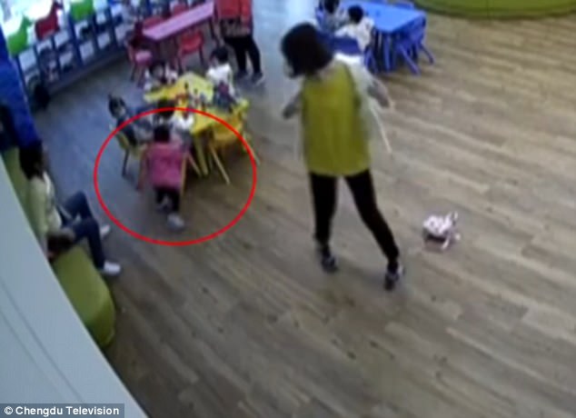 The girl turns around and hits her head towards a table as she is pushed by the teacher