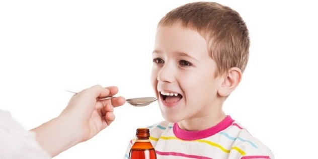 мальчик улыбаясь пьет сироп от кашля
