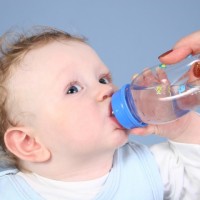 Малыш пьет воду из бутылочки