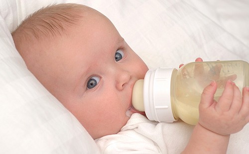 Малыш пьет молочную смесь из бутылки