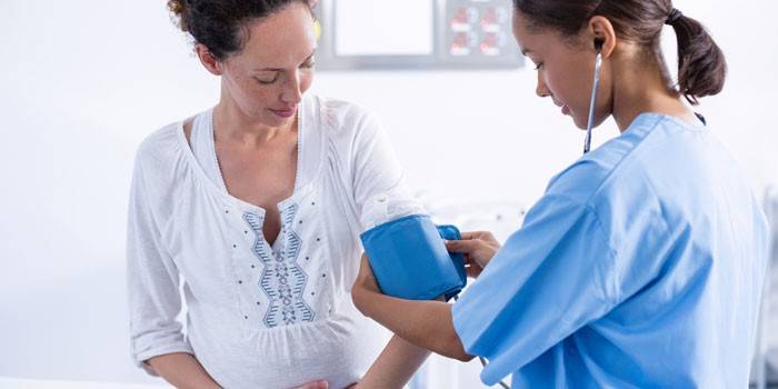 Медик измеряет давление беременной женщине