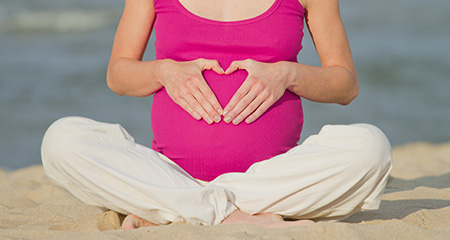 беременная женщина сидит на пляже