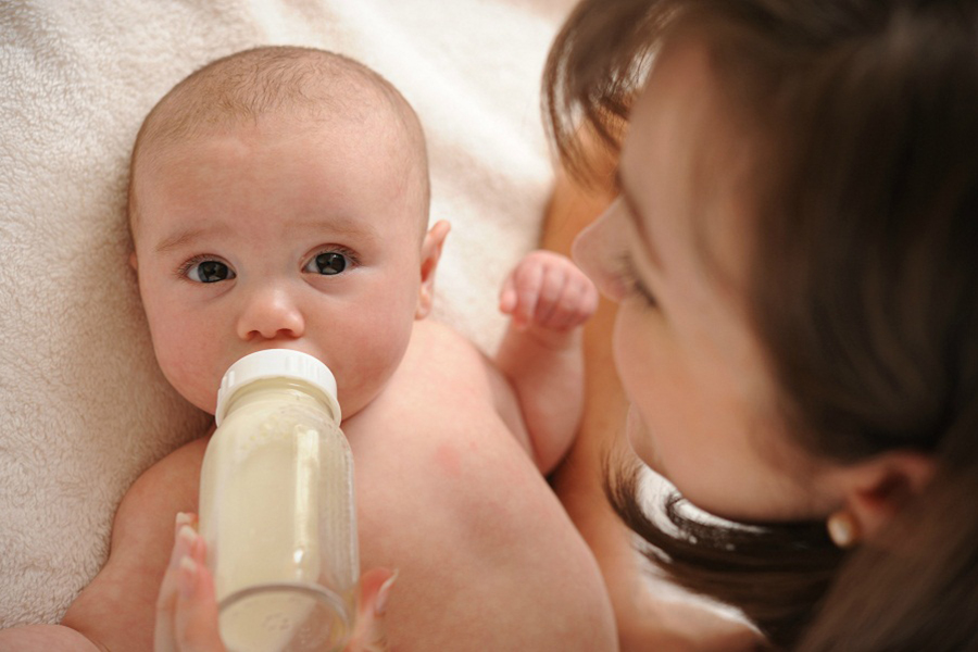 Женщина кормит ребенка из бутылочки