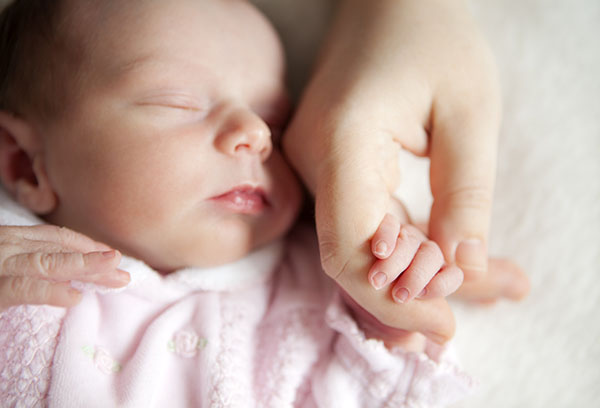 Спящий малыш держит мамину руку